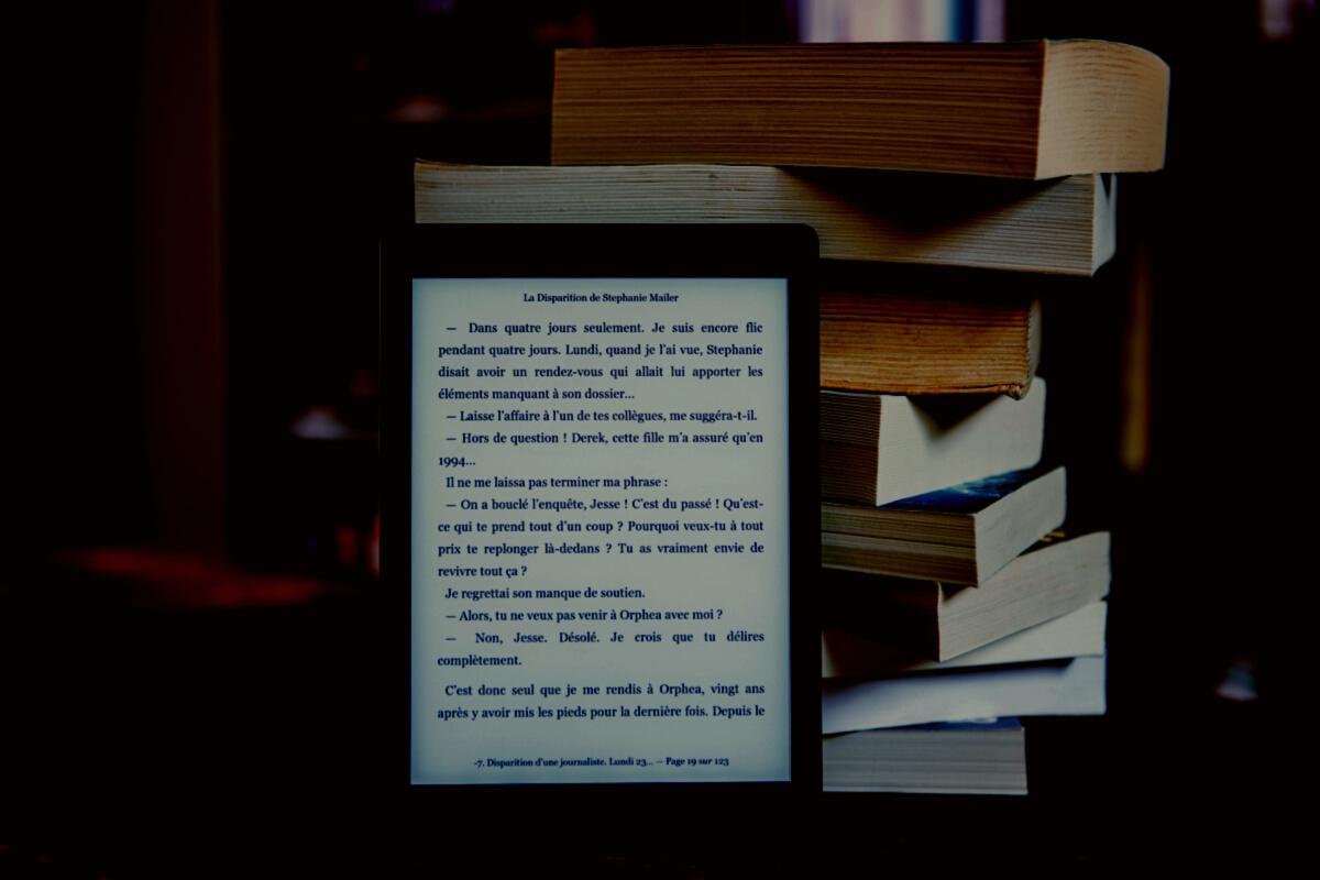 Black Tablet Computer Behind Books